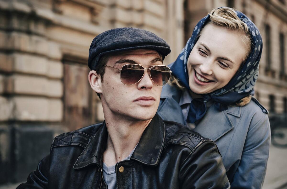 Ulla Wolf (Elisa Schlott) strahlt Tommy Weidner (David Schütter) an, als sie hinter ihm auf dem Motorrad sitzt